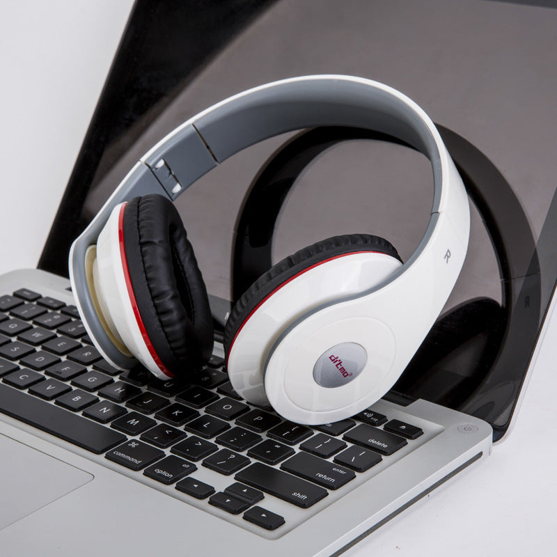 White wired gaming headphones with padded ear cups and integrated microphone resting on laptop keyboard