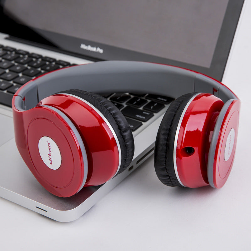Red wired over-ear gaming headphones with integrated microphone resting on silver laptop keyboard