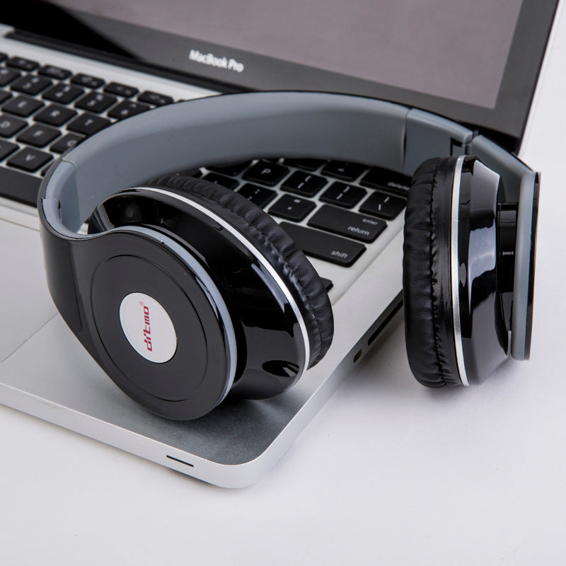 Black wired over-ear gaming headphones with padded cushions resting on laptop keyboard near trackpad