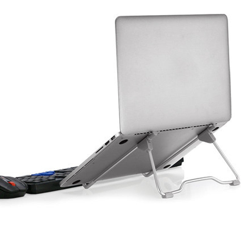 Silver adjustable laptop stand supporting closed laptop with wireless keyboard and mouse on white background